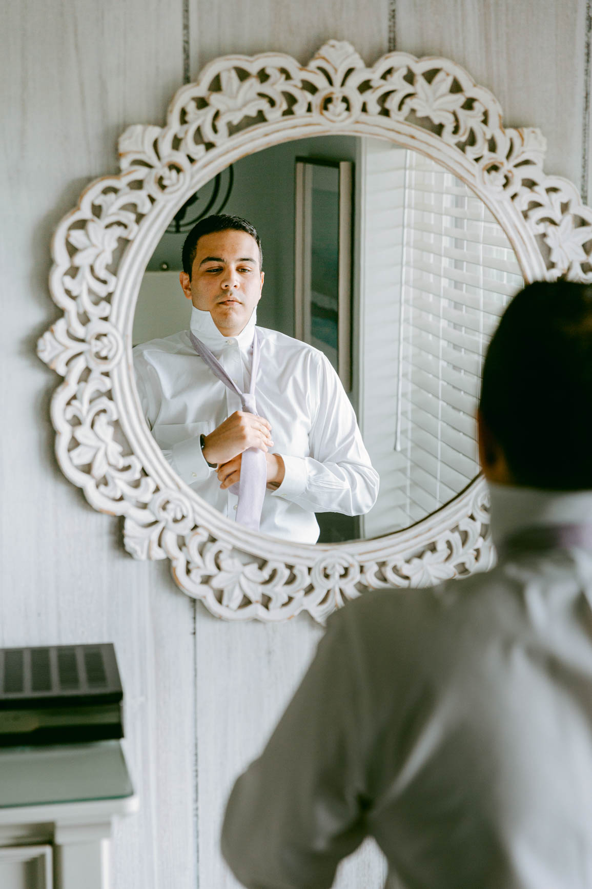 groom putting tie on at a lake house elopement shot by Nhieu Tang Photography | nhieutang.com