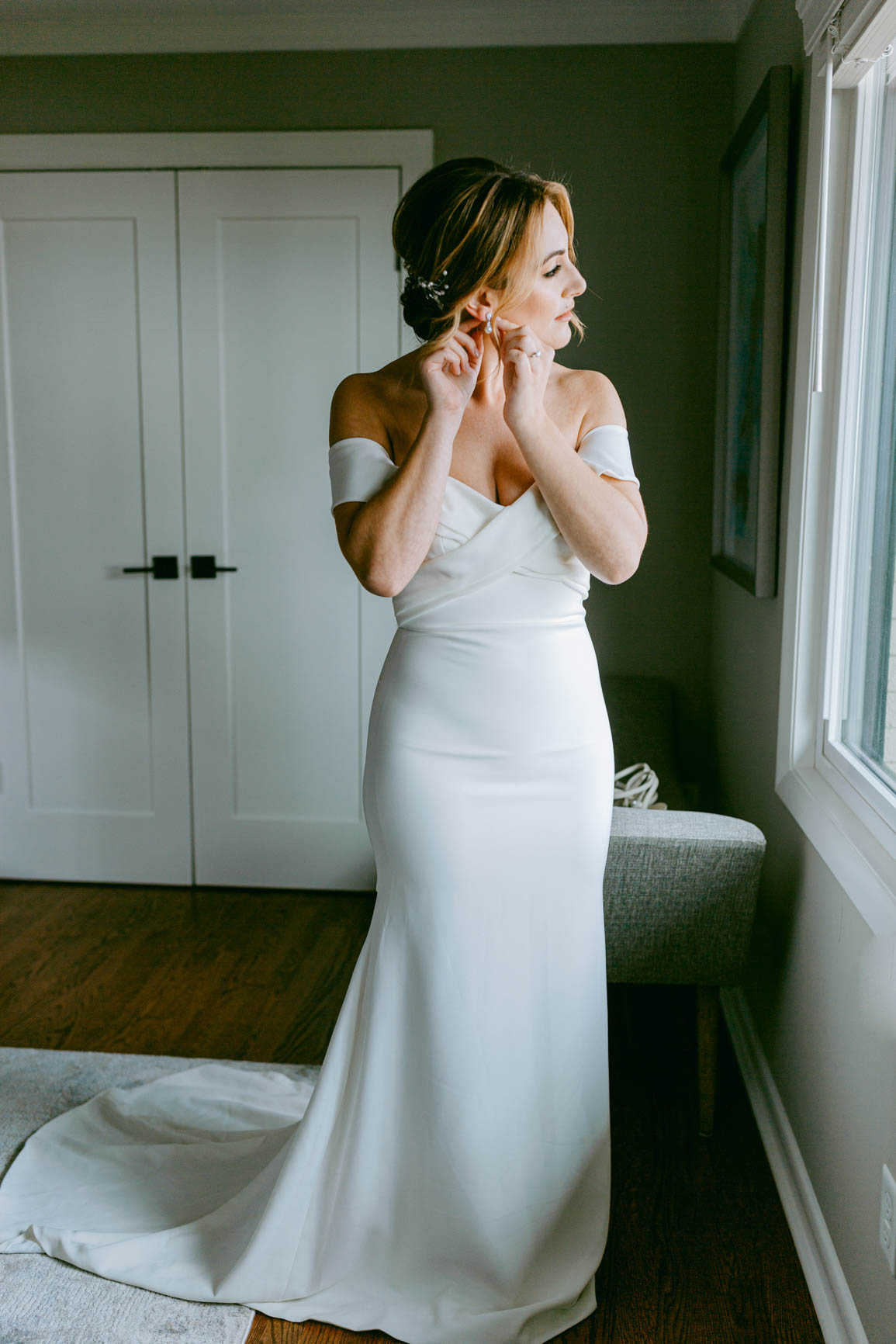 bride putting on earrings in Mooresville, NC lake house shot by Nhieu Tang Photography | nhieutang.com