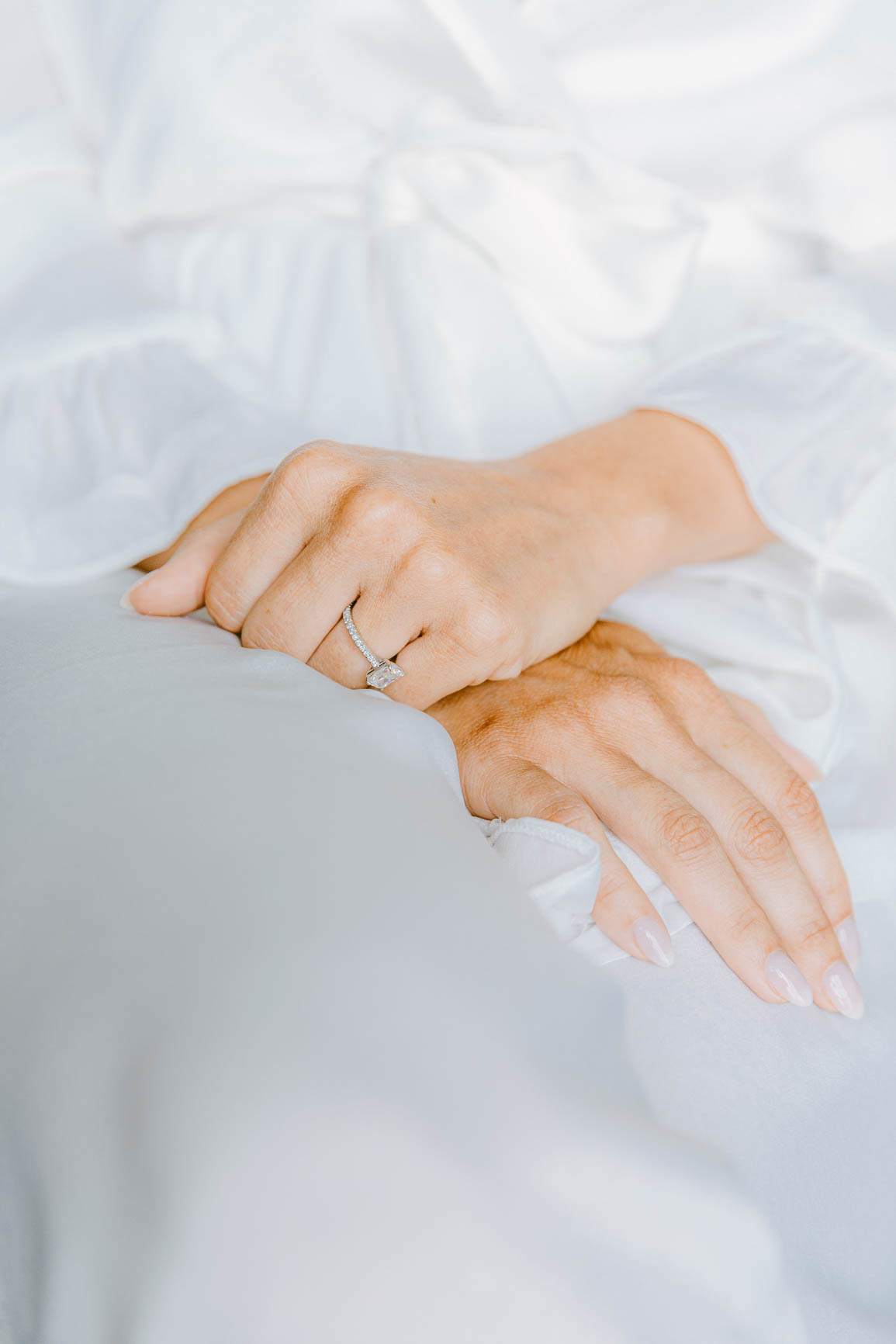 Bride in white robe wearing an emerald engagement ring shot by Nhieu Tang | nhieutang.com