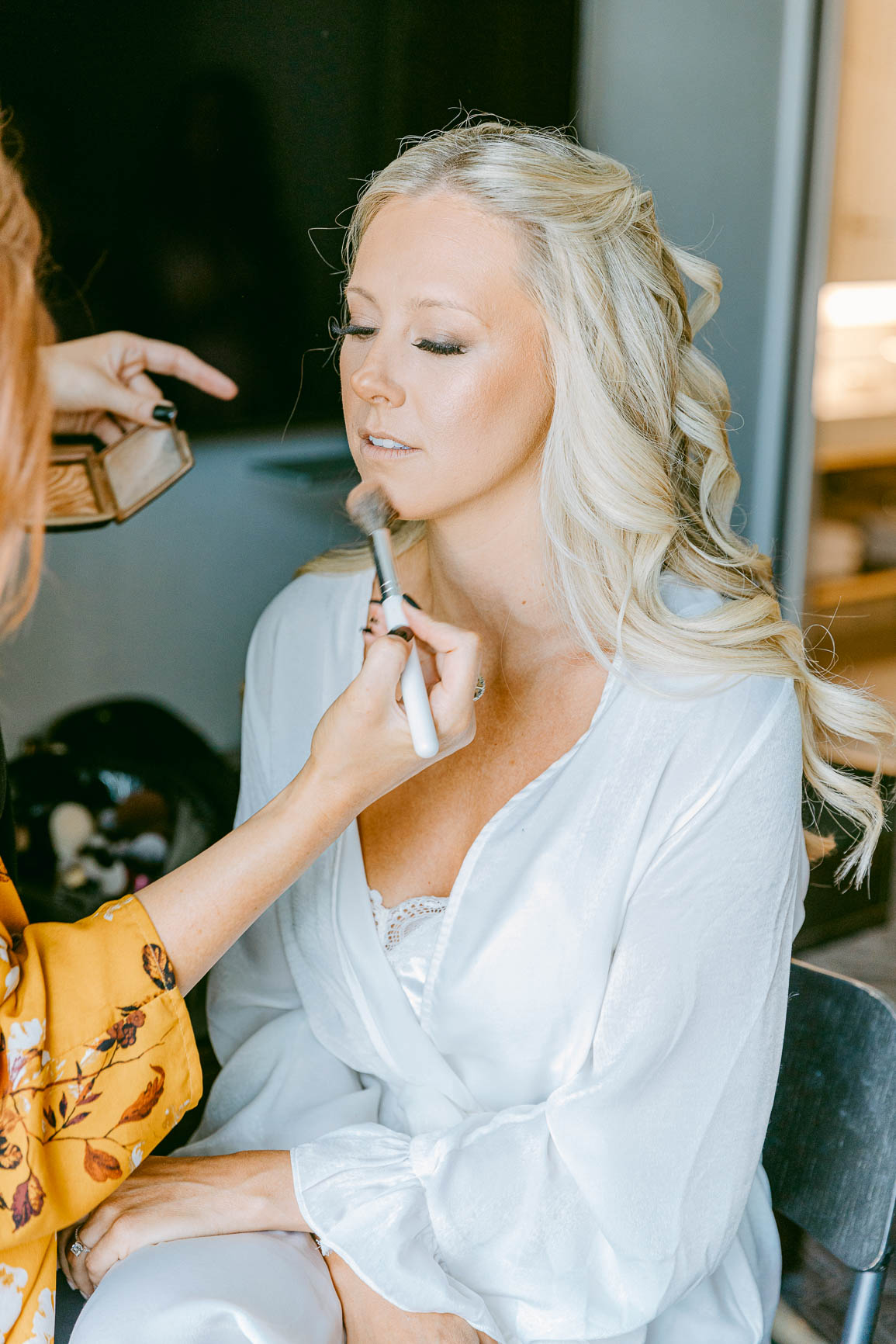 Bride getting ready in white robe at the Kimpton Tryon park hotel shot by Charlotte wedding photographers | nhieutang.com