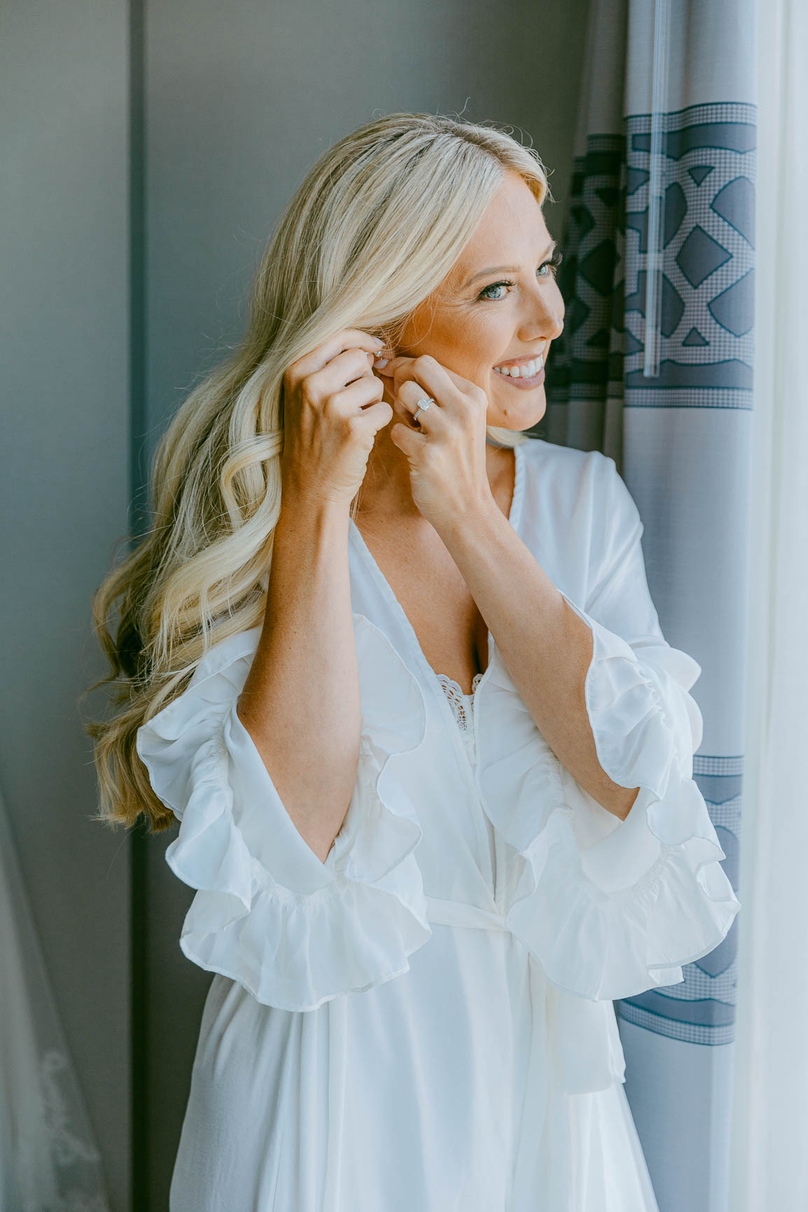 Bride putting on earrings at the Kimpton Tryon park hotel suite shot by Nhieu Tang Photography | nhieutang.com