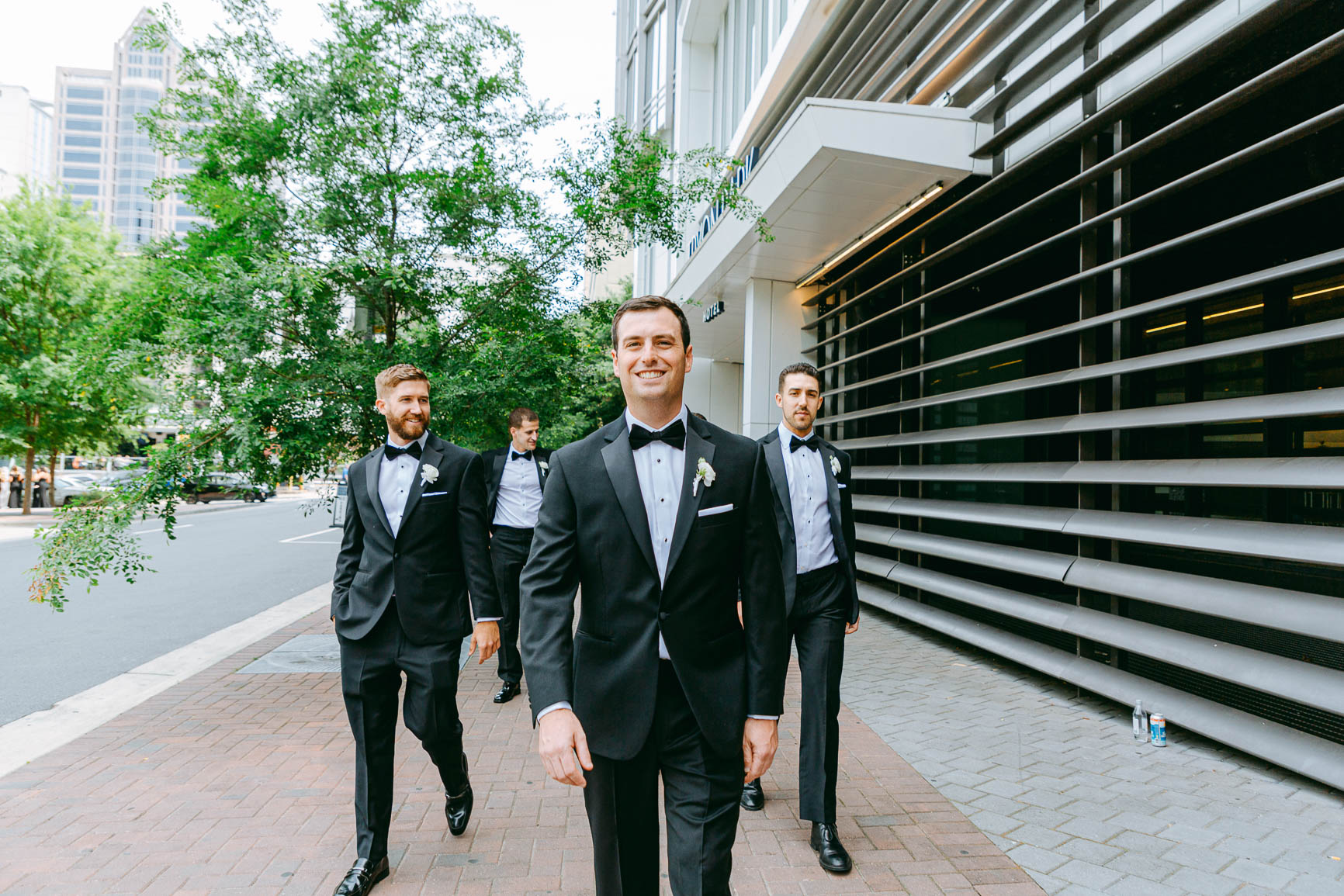 groom and groomsmen walking in uptown Charlotte nc shot by Nhieu Tang Photography | nhieutang.com