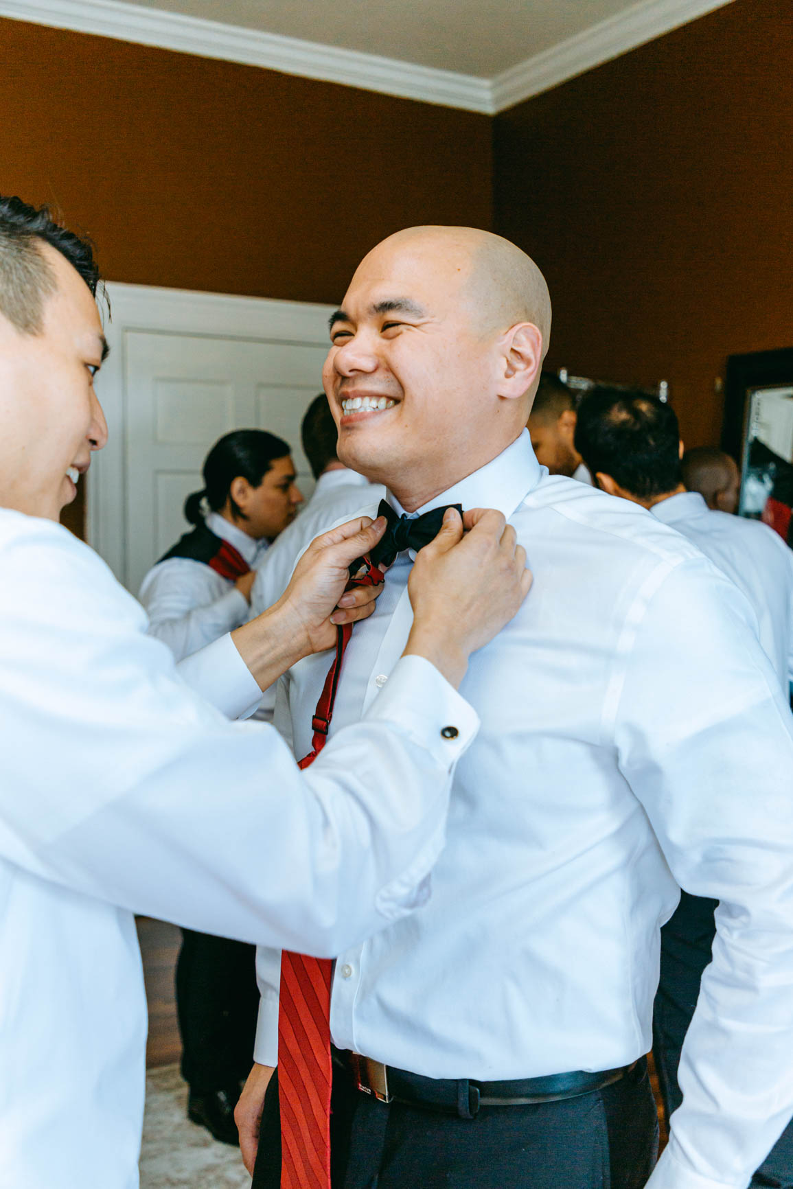 groom putting on bowtie at Separk Mansion in Gastonia NC shot by Nhieu Tang Photography | nhieutang.com